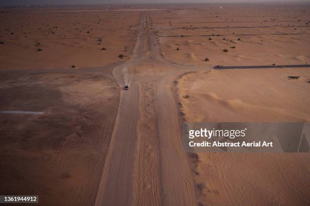 aerial view showing an off-road vehicle driving on a desert track, dubai, united arab emirates - desert highway stock pictures, royalty-free photos & images