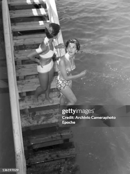 English actress Jean Simmons , wearing a swimming suit, entering the water, Lido, Venice, 1950.