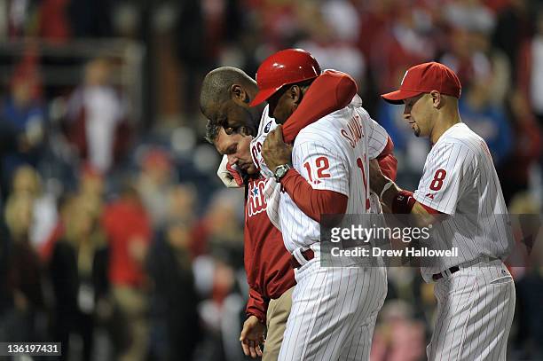 Ryan Howard of the Philadelphia Phillies is assisted off of the field after he was hurt on the last play of the game as the Phillies lost 1-0 against...