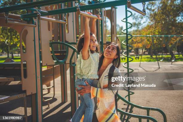 mother helps daughter on jungle gym - filipino girl stock pictures, royalty-free photos & images