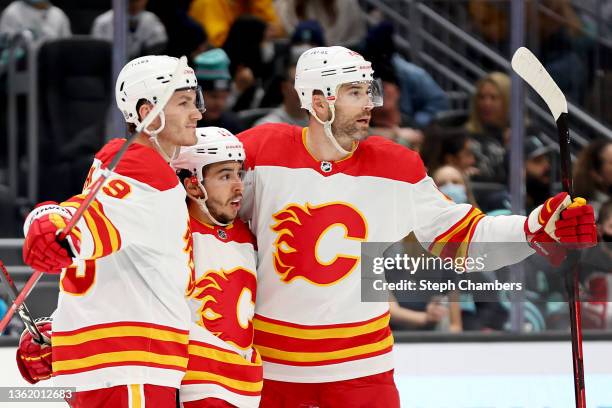 Johnny Gaudreau of the Calgary Flames celebrates his goal with Erik Gudbranson and Matthew Tkachuk during the first period against the Seattle Kraken...