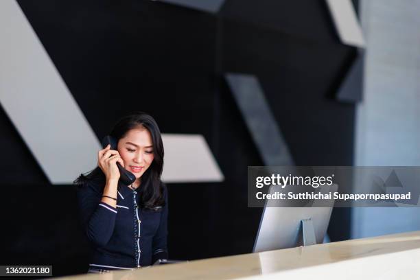 asian female reception answer the telephone at the hotel lobby. - reception stockfoto's en -beelden