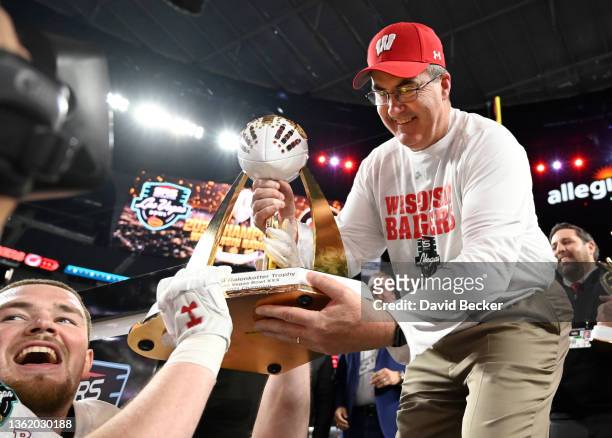 Linebacker Noah Burks of the Wisconsin Badgers is handed the championship trophy from head coach Paul Chryst after the team defeated the Arizona...