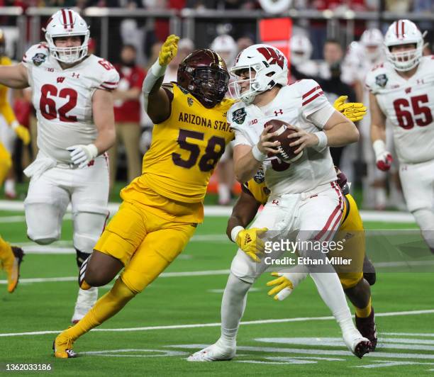 Quarterback Graham Mertz of the Wisconsin Badgers is sacked by defensive linemen Joe Moore and B.J. Green II of the Arizona State Sun Devils during...