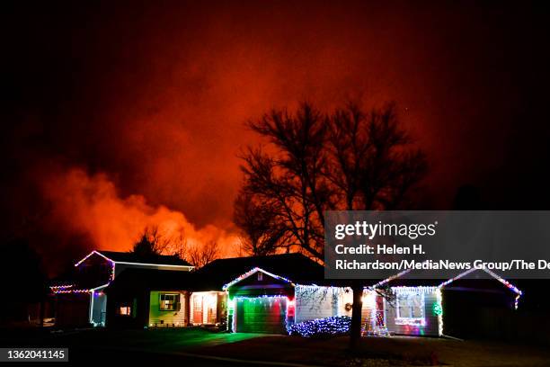 Christmas lights adorn a house as fires rage in the background on December 30, 2021 in Louisville, Colorado. Fierce winds have whipped wildfires in...