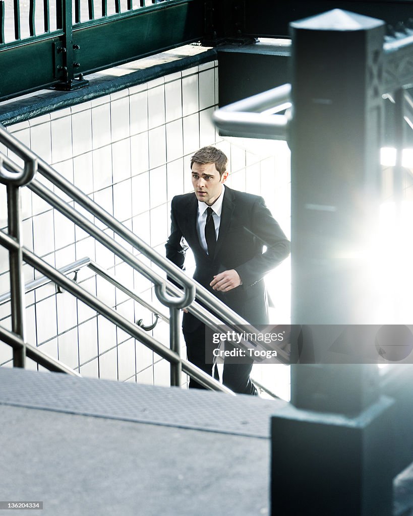 Businessman running up subway stairs