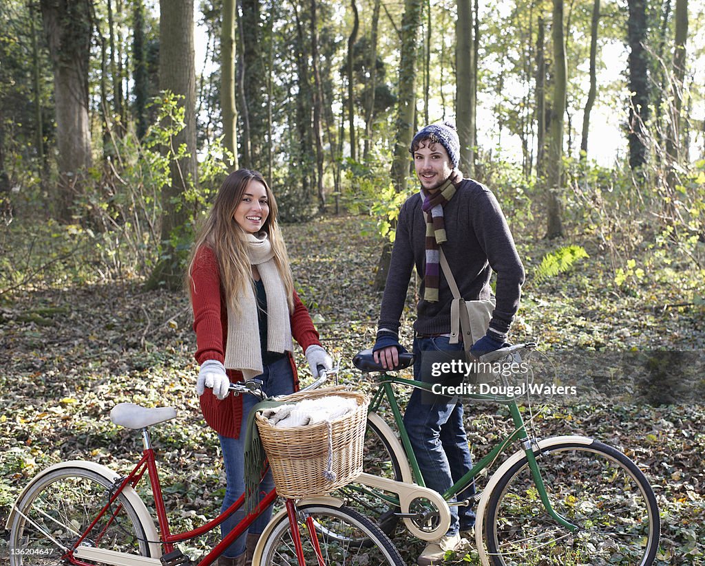 Couple in Autumn woodland with vintage bikes.