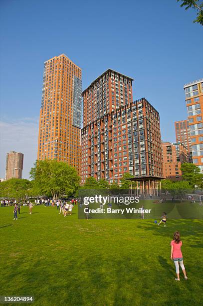 children playing on lawn in city park near towers. - battery park stock pictures, royalty-free photos & images
