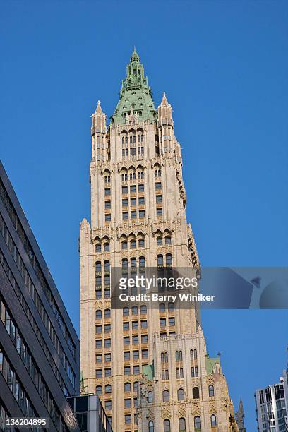 looking up at tall building against blue sky. - woolworth building stockfoto's en -beelden