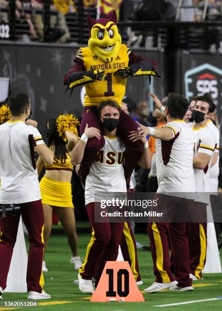 An Arizona State Sun Devils cheerleader carries mascot Sparky the Sun Devil during the SRS Distribution Las Vegas Bowl against the Wisconsin Badgers...