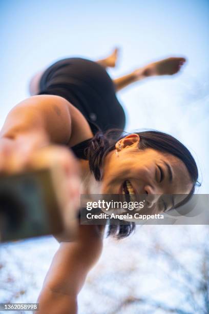 gymnast performing handstand outdoors seen from below - frau gymnastik stock-fotos und bilder