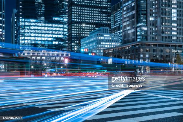 illuminated skyscrapers and light trails in front of tokyo station - townscape stock pictures, royalty-free photos & images