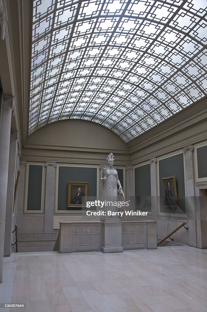Curved glass ceiling above paintings and statue.