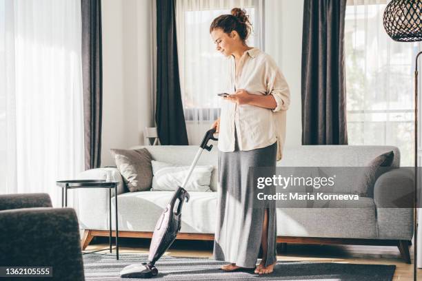 woman doing house work. woman talking on cell phone while vacuuming floor. - talk phone flat imagens e fotografias de stock