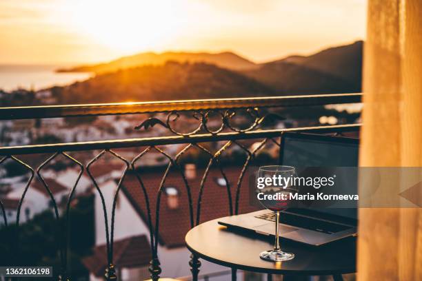 glasses of wine and laptop on a balcony at sunset. - suite photos et images de collection