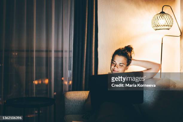 woman using laptop at home at night. - lamp fotografías e imágenes de stock