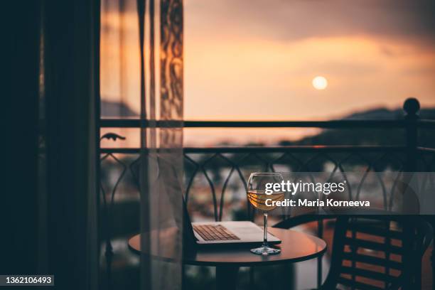 glasses of wine and laptop on a balcony at sunset. - hotel balcony stock-fotos und bilder