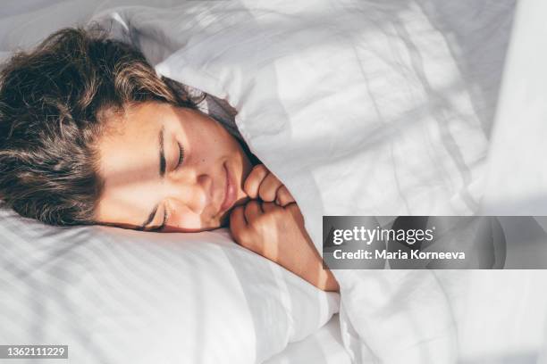 lady sleeps in bed tossing turning in dream under blanket - woman pillow over head stock-fotos und bilder