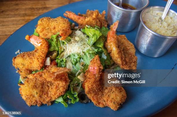 coconut breaded prawns on a salad of lettuce, cherry tomato, mixed olives and parmesan cheese with sides of a spicy salsa sauce and a creamy risotto - coco rallado fotografías e imágenes de stock