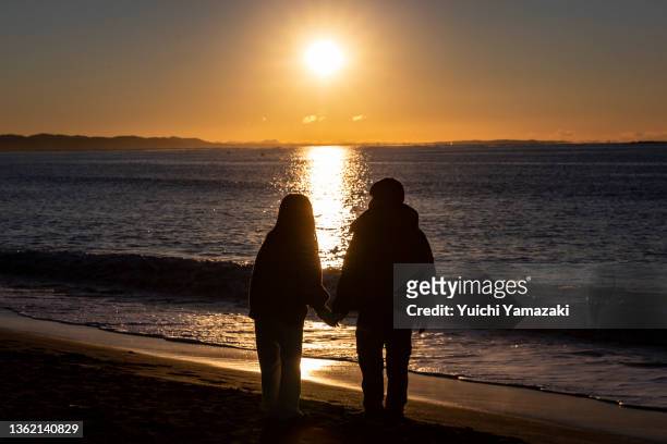 Couple watches the sunrise at Southern Beach Chigasaki on January 01, 2022 in Chigasaki, Japan. As Covid-19 coronavirus infections remain low across...