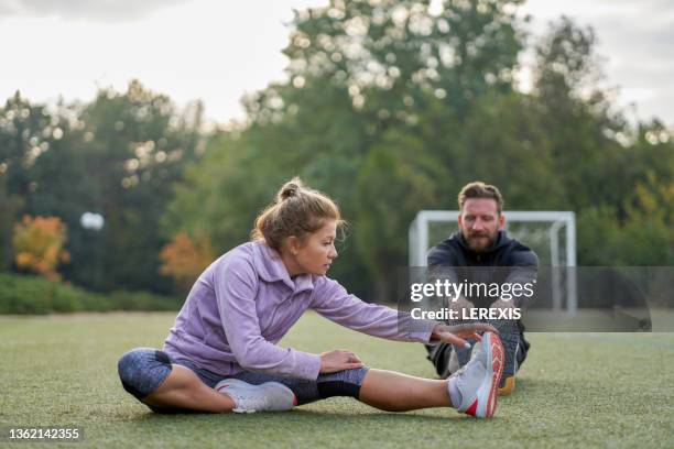 middle-aged woman doing stretching exercises - estirar fotografías e imágenes de stock