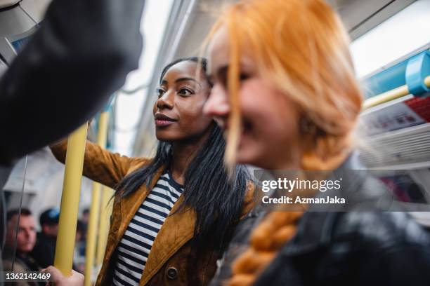 schwarze und rothaarige frau pendelt mit der londoner u-bahn - busy tube stock-fotos und bilder