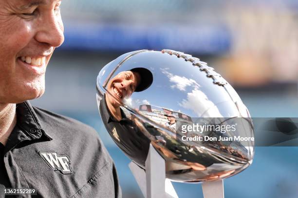 Head Coach Dave Clawson of the Wake Forest Demon Deacons smiles at his reflection of himself from the championship trophy after the game against the...