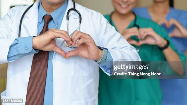 medicine, people, charity, health care and cardiology concept - doctors hands making heart shape - kardiologe stock-fotos und bilder