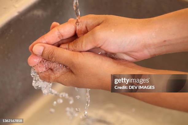 human hands being washed under stream of pure tap water - stream body of water fotografías e imágenes de stock