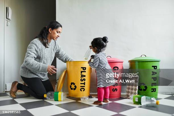 little girl helping her mother doing the recycling at home - color coded 個照片及圖片檔