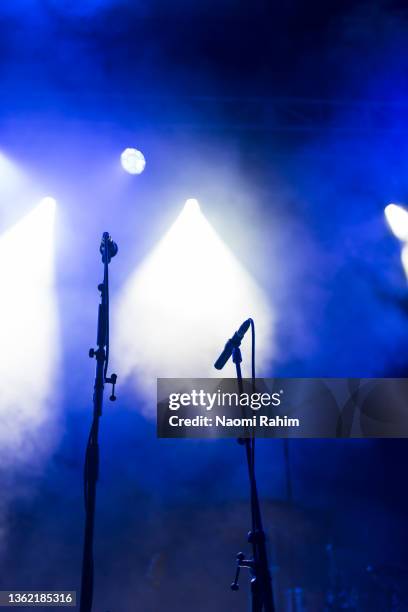 two microphones stands on a concert stage under blue and white spotlights - melbourne festival stock-fotos und bilder