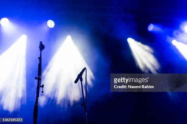 concert microphones stands on a blue stage under spotlights - stand up comedy stockfoto's en -beelden