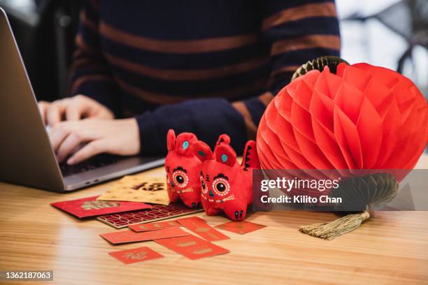 woman using laptop with chinese new year decorations on the desk - blessing of the animals stock pictures, royalty-free photos & images