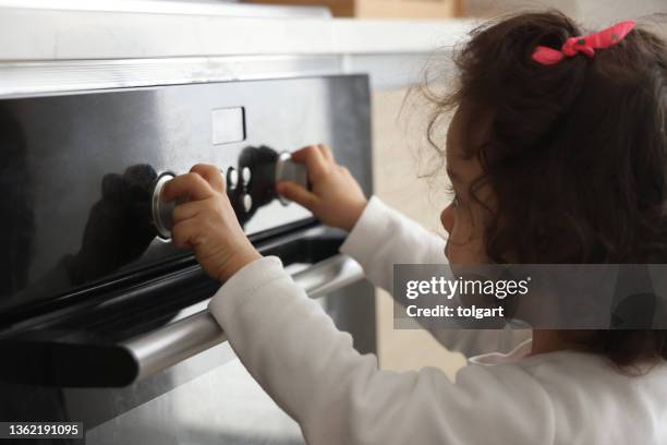 little girl turns the oven button - child proof imagens e fotografias de stock