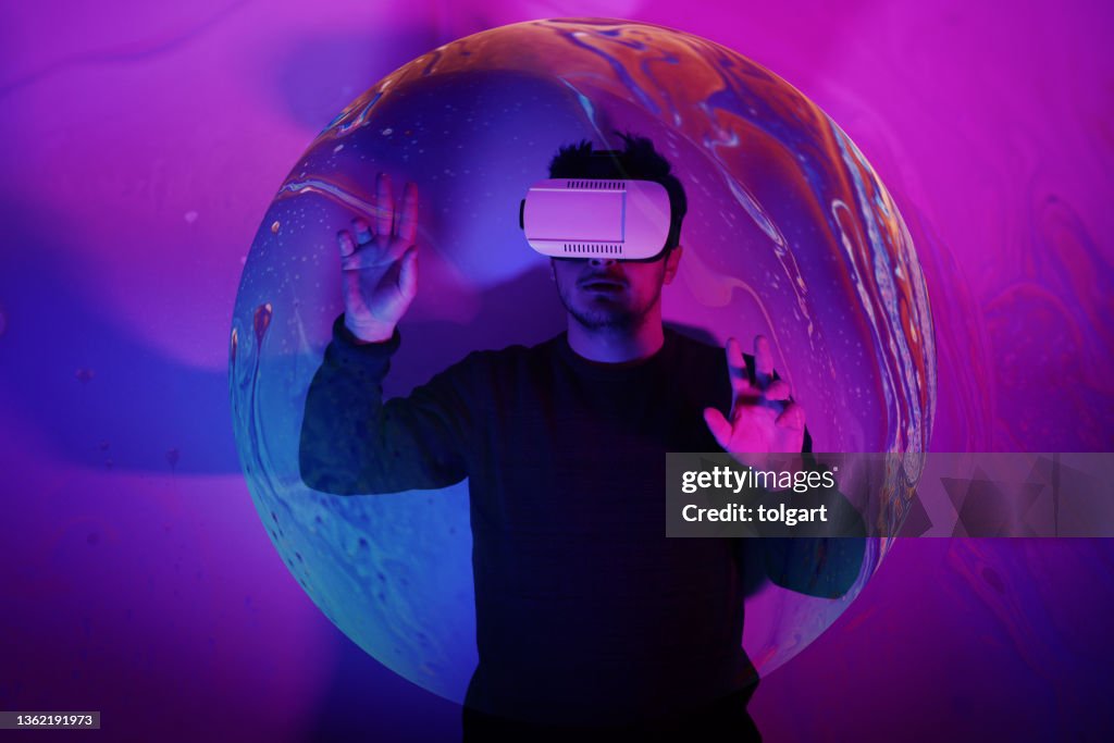 He is discovering metaverse by using VR glasses under neon lights