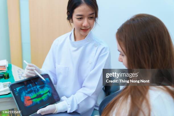 dentist showing teeth x-ray on digital tablet screen,dental consultation in dentist office. - dental imaging stock pictures, royalty-free photos & images