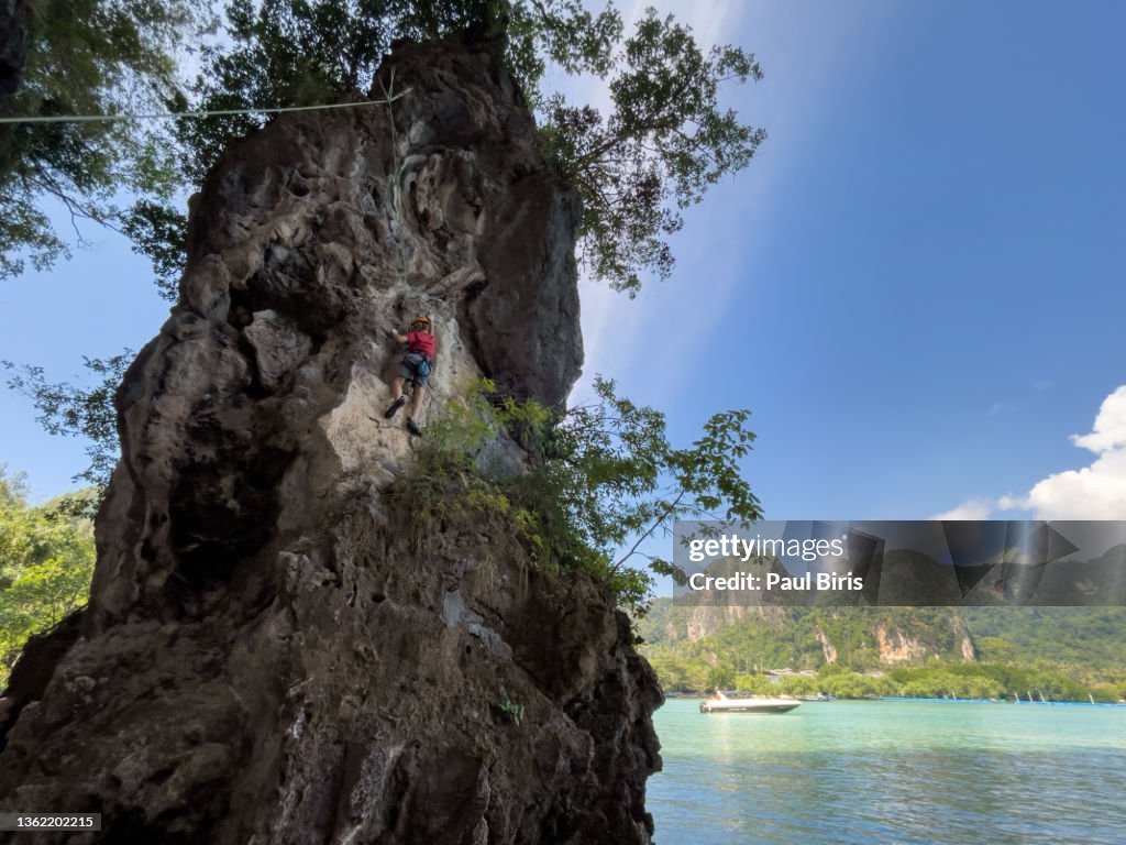 Young boy climber climbing on the rock outdoors, Railay, Krabi, Thailand