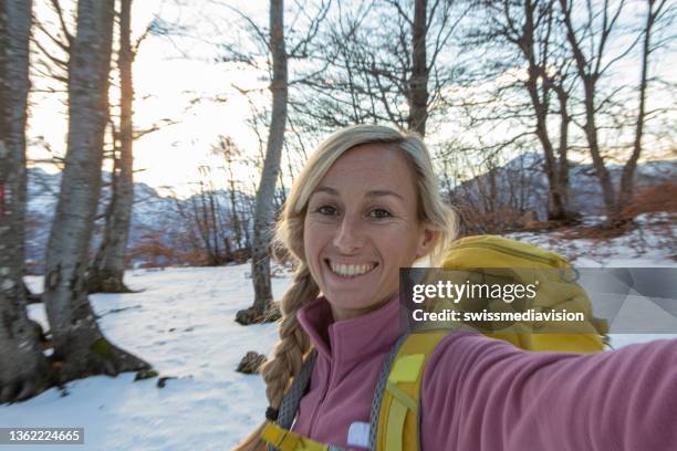 冬のハイキング中に森の中でセルフィーを撮る若い女性 - 宣伝イベント ストックフォトと画像