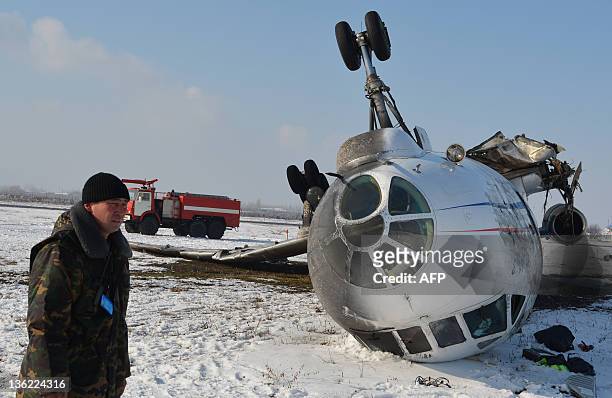 Security guard stands near an overturned Russian-made Tupolev Tu-34 passenger jet at the airfield outside the southern Kyrgyz city of Osh, on...