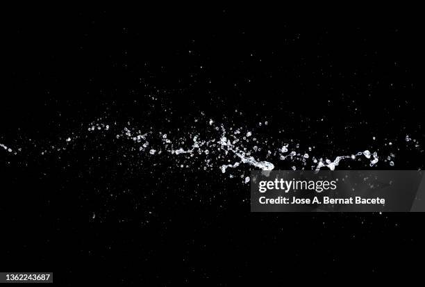 drops and splashes of water floating in the air on a black background. - water puddle stock pictures, royalty-free photos & images