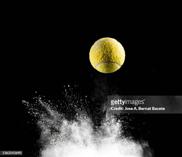 impact and rebound of a ball of tennis on a surface of land and powder on a black background - tennis racket stock-fotos und bilder