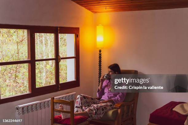 woman in pajamas with her foot bandaged and raised recovering from an injury at home - broken lamp stock-fotos und bilder