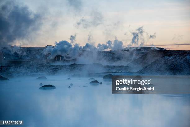 icelandic geothermal blue hot spring in lava stones covered with snow at sunset - mud foto e immagini stock