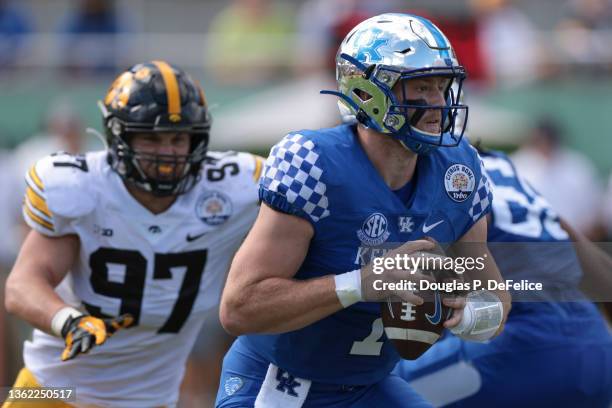 Will Levis of the Kentucky Wildcats scrambles with the ball as Zach VanValkenburg of the Iowa Hawkeyes defends during the first quarter in the Citrus...