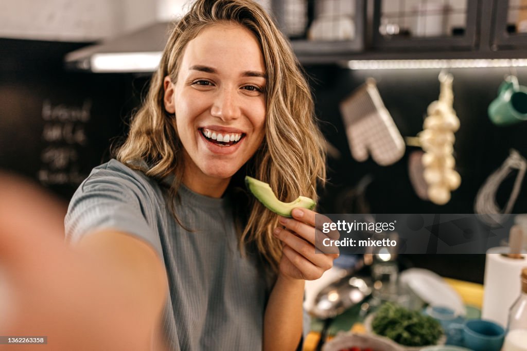 Woman eating avocado and taking selfie