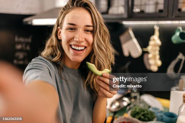 woman eating avocado and taking selfie - selfie indoors stock pictures, royalty-free photos & images