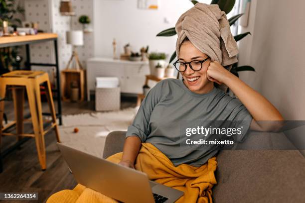 frau sitzt auf sofa mit laptop - towel stock-fotos und bilder