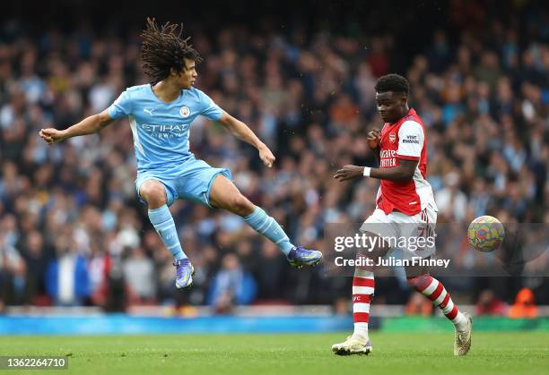 Bukayo Saka of Arsenal is challenged by Nathan Ake of Manchester City during the Premier League match between Arsenal and Manchester City at Emirates...