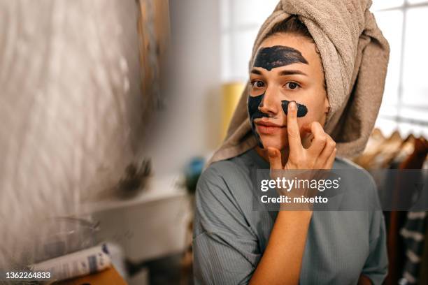 woman applying black face mask - pores stockfoto's en -beelden