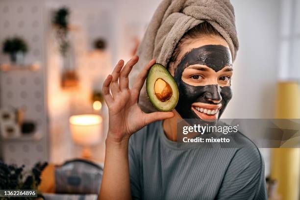 woman with black face mask holding avocado - peel stock pictures, royalty-free photos & images